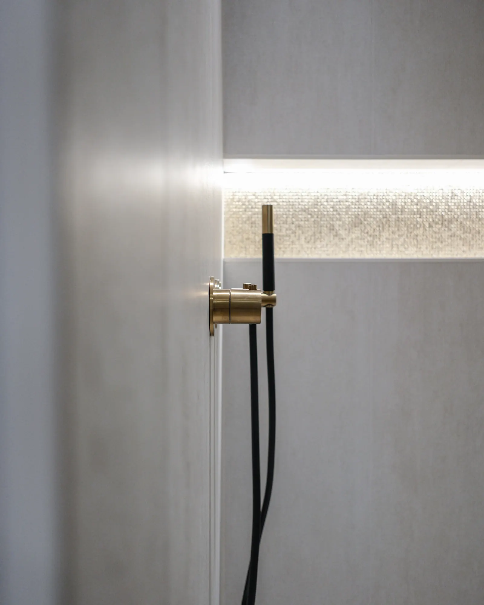 Zwarte handdouche met messing aansluiting en verlichte nis