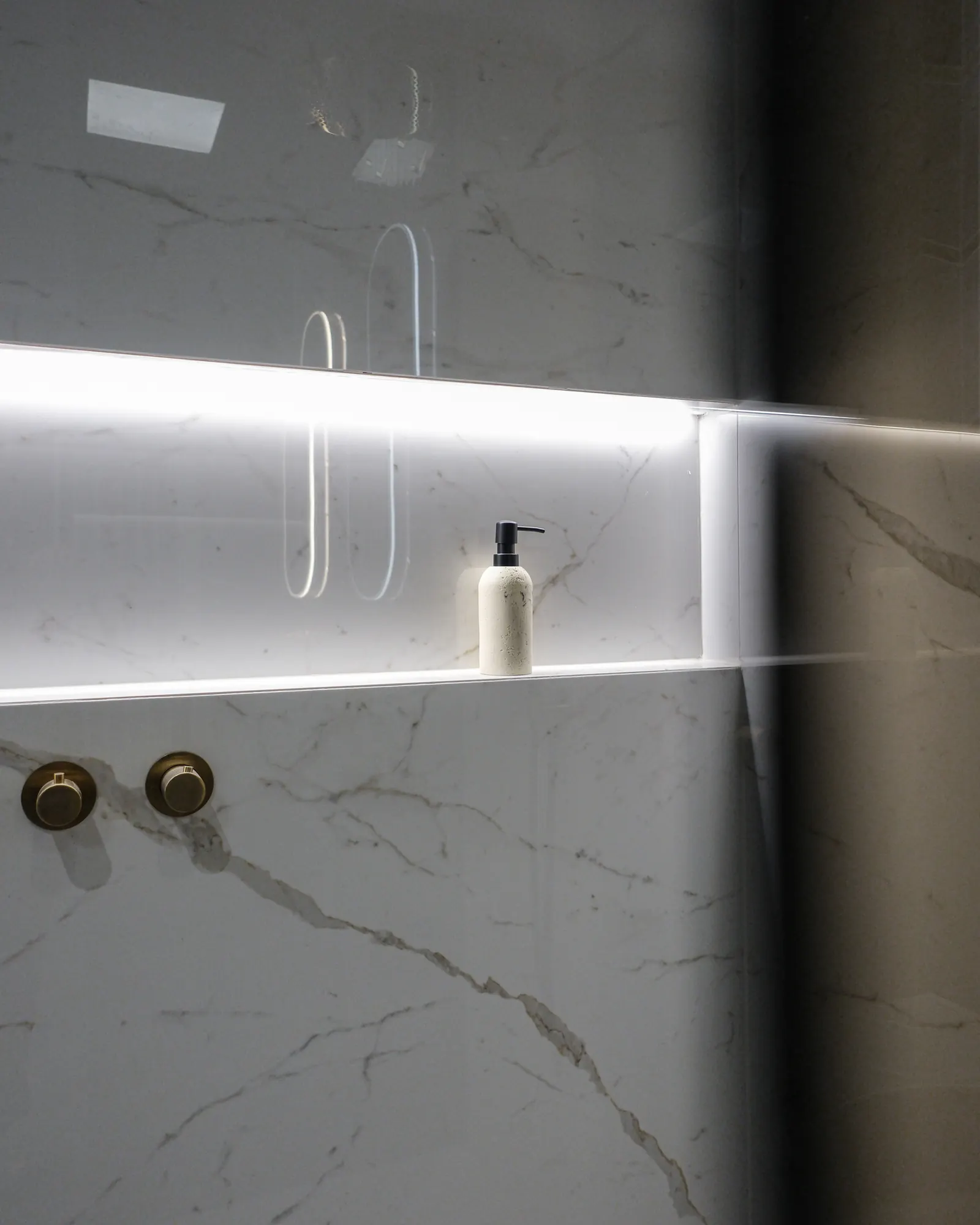 Verlichte nis met messing thermostaat in marmerlook tegels